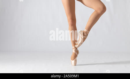 Close-up of dancing legs of ballerina wearing white pointe on a white background. Ballet dancer and practice concept background Stock Photo