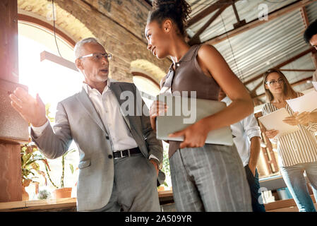 Business professionals. Two colleagues discussing new project while walking standing in the office corridor Stock Photo