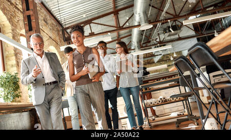 Business partners. Business people discussing something while walking with colleagues through the office corridor Stock Photo