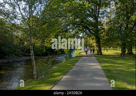 People walking along footpath beside the River Greta in Fitz Park Keswick Lake District National Park Cumbria England UK United Kingdom Great Britain Stock Photo