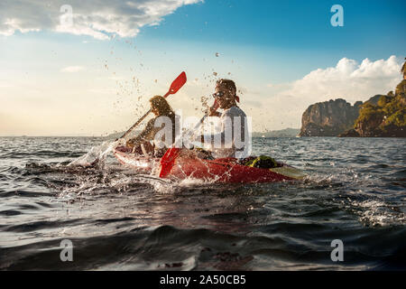 Happy couple is having fun and walks on sea kayaks at sunset bay