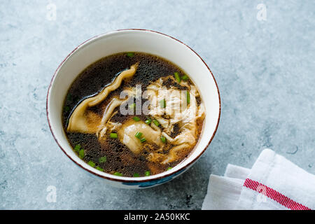 Asian Food Wonton Soup with Bok Choy and Chives in Porcelain or Ceramic Bowl. Traditional Dish Cuisine. Stock Photo