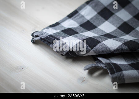 Checked black and white kitchen towel on wooden surface. Selective focus Stock Photo