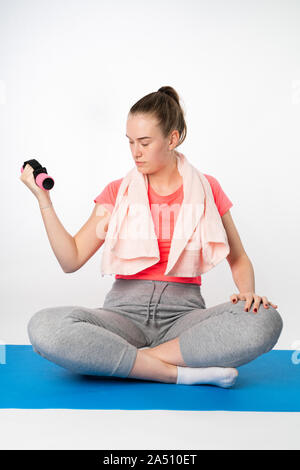 young woman does a barbell exercise on a yoga mat Stock Photo