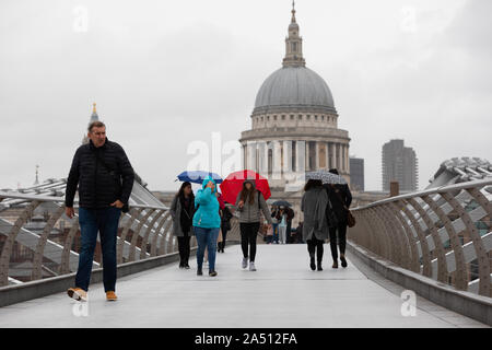 London. UK. 17 October 2019. Tourists walking across Millennium Bridge, opposite St Paul's Cathedral in London during heavy rain and wet weather this afternoon. Credit: Alamy Live News Stock Photo
