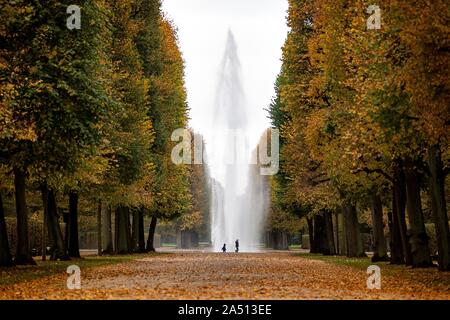 Hanover, Germany. 17th Oct, 2019. Two walkers walk through the manor house gardens in front of a water fountain of a fountain. Credit: Sina Schuldt/dpa/Alamy Live News Stock Photo