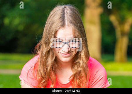 A young woman in a park looks into the camera Stock Photo