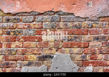 Old brick wall with peeling plaster, grunge background. Stock Photo