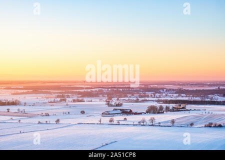 Wintery sunset over a rural landscape with fields and farms Stock Photo