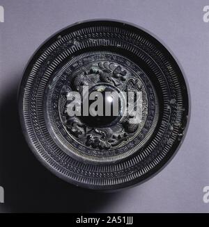 Mirror with Two Dragons and a Tiger, 3rd Century. Inscription: I, Master Zhang, produced this mirror, When alien tribes in four corners were being subjugated. Let us praise our Lord, for the people are given respite. After quelling the Hu and Qiang [tribes], he will restore peace on earth. May you reach the high office and receive your just reward. May you [gain the power to] protect your parents and descendants from harm. May your joy be endless. Stock Photo