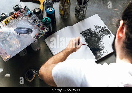young painter works on a book on the grey floor painting of many color Stock Photo