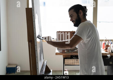 young painter working with big brush on a white canvas that we have pu Stock Photo