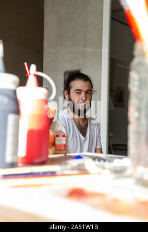 young man painter works in his workshop on a white canvas painting gra Stock Photo