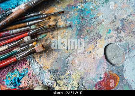used and painted brushes on a palette of colours Stock Photo