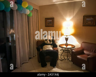 Man dressed as a panda sitting on the couch. Stock Photo