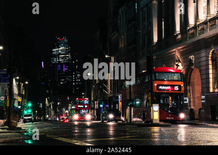 typical london buses commuting at night in central london with skyline Stock Photo