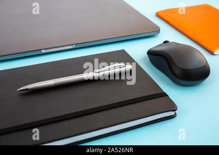 Desk with laptop, notebook, agenda, pen, bluetooth mouse, orange notebook. Office mock up, empty document. Stock Photo