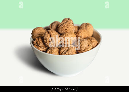 White bowl full of nuts on a white and green background Stock Photo