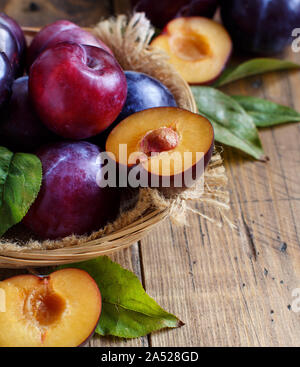 Fresh plums with leaves on a wooden table close up Stock Photo