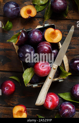 Fresh plums with leaves on a wooden table close up Stock Photo