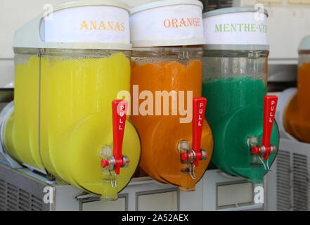 dispenser with many ice with syrup with text in french that means pineapple, orange and mint Stock Photo