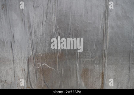 grunge winked bumpy ripped glued air pockets silver painted paper on a wall Stock Photo