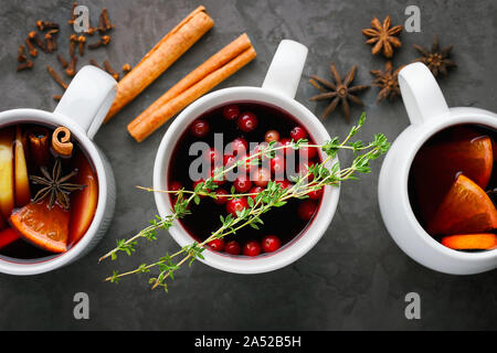 Christmas hot mulled wine drink in a cups with orange citrus,apple,cinnamon sticks and stars anise on dark gray concrete background top view Stock Photo