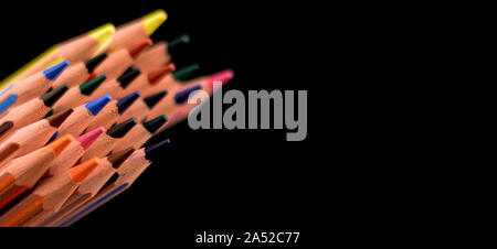 Many sharpened colored pencils to the left of the image with a black background Stock Photo