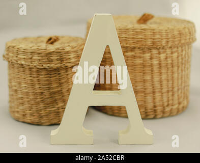 Letter A uppercase of corporeal wood with two wicker baskets behind it, on white background Stock Photo