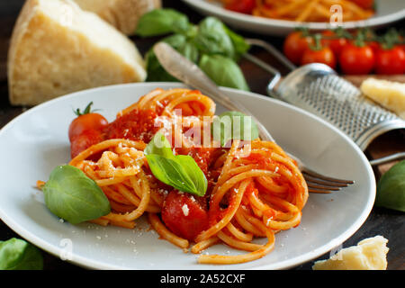 Spaghetti pasta with tomato sauce, basil and cheese on a wooden table