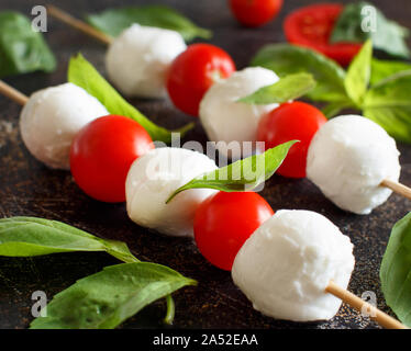Caprese skewers with tomatoes, mozzarella balls, basil and spices on ...
