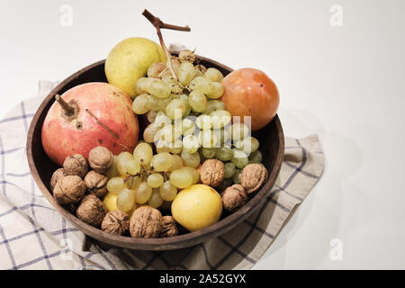 Autumnal fruits in a wooden bowl over a white background Stock Photo