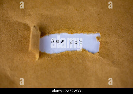 The text, new job, appears behind torn brown paper Stock Photo