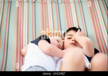 Brothers laying together with somber look in hammock Stock Photo