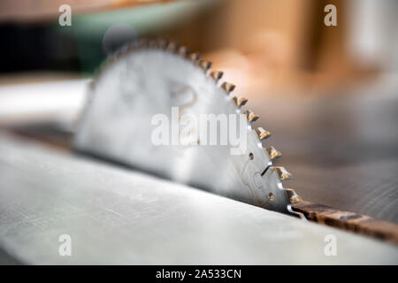 Close up detail of the blade on a circular saw showing the teeth in selective focus in a woodworking workshop Stock Photo