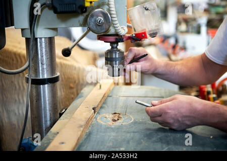 Carpenter changing the bit on a vertical drill in a woodworking workshop in a close up on his hands Stock Photo