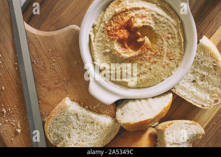 Hummus with sourdough bread on a wooden cutting board. Stock Photo