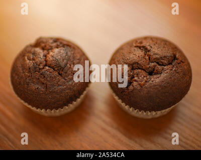 two chocolate muffins on the brown wooden table. Stock Photo