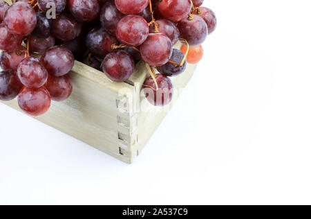 Ripe red grapes in a wooden box isolated on white background Stock Photo