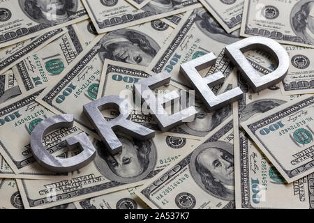 The word GREED laid with aluminium letters on the US dollar banknotes background - with selective focus and diagonal composition. Stock Photo