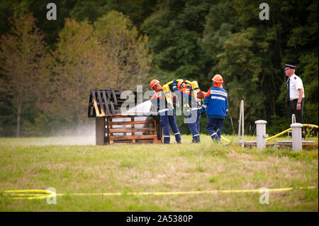 Germany, Niederstetten, Baden Wurttemberg. September 2019 Young firefighters in training with fire hose by extinguishing the fire. Stock Photo