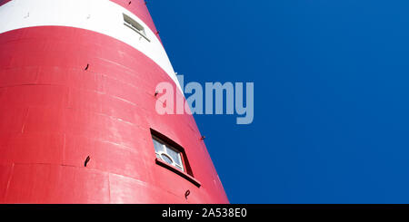 detail of a red and white lighthouse with blue sky in the background Stock Photo