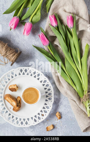 Beautiful pink tulips with a little cup of espresso coffee and some biscotti cookies. The view if from above, flat lay perspective. There is also a vi Stock Photo