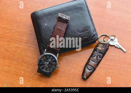 Brown wallet, watch and key holder on wooden desk. Stock Photo