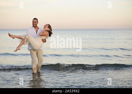 beautiful pregnant woman and her man walk on the beach on sunset Stock Photo