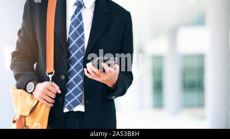 Young businessman on smartphone walking in street using app texting on smartphone. Stock Photo