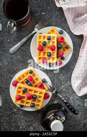 Waffles with blueberries, raspberries, maple sirup and tea cup. Top view. Stock Photo