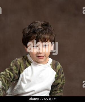 Vertical studio shot of a suspicious but cute four year old on a brown background with copy space. Stock Photo