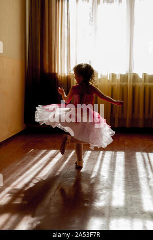 KHARKIV, UKRAINE - MARCH 6, 2019: Cute little girl dreaming of becoming a ballerina. Child girl in a white tutu dancing. Baby girl is studying ballet. Stock Photo