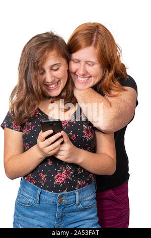 Vertical studio shot of a mother leaning on her daughter’s shoulder watching her use her cell phone.  They are both laughing.  White background. Stock Photo